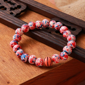 Macro detail of spotted beads and orange basketball bead on a rustic wooden tray