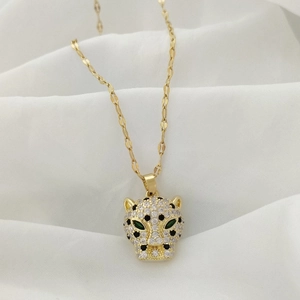 Macro detail of gold panther pendant with white cubic zirconia and green gem eyes