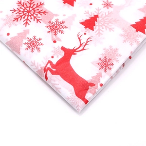 Macro detail of Christmas wrapping paper featuring red reindeer and snowflake prints