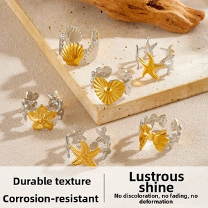 Close-up of gold star and seashell charms on mixed metal adjustable ring set