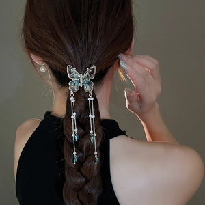 Elegant gold butterfly hair claw with pearls and turquoise tassels on braided hair