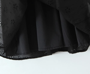 Détail de la robe noire à col en V avec broderie florale délicate et tissu en dentelle ajourée
