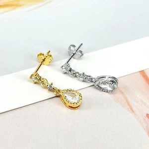 Detailed close-up of water-drop earrings with clear cubic zirconia in gold and silver