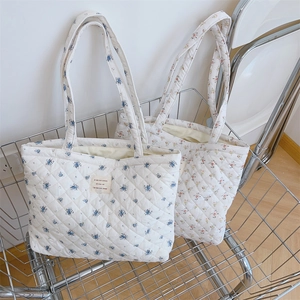 Gros plan détaillé de deux grands sacs fourre-tout matelassés fleuris dans un panier