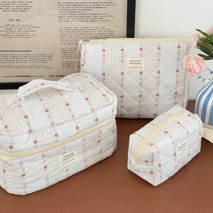 Detailed set of three floral quilted makeup bags with aesthetic fabric label on desk