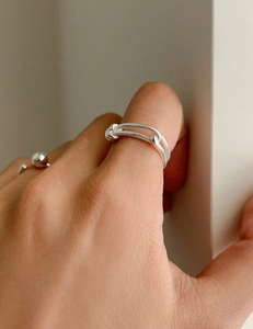 Macro detail of silver double-layered knotted ring showing snake chain texture and metal shine