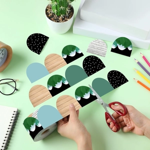 Scalloped border stickers for bulletin boards being trimmed with scissors for DIY use