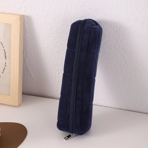 Close-up of a dark blue velvet pencil case with a quilted square pattern and metal zipper