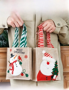 Detail of burlap Christmas gift bags featuring 3D snowman and Santa Claus embroidery