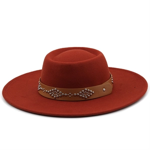 Close-up of red wool felt fedora featuring a brown leather band with silver metal rivets