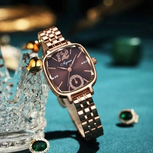 Détail d'une montre tonneau or rose avec cadran brun soleil et index en strass