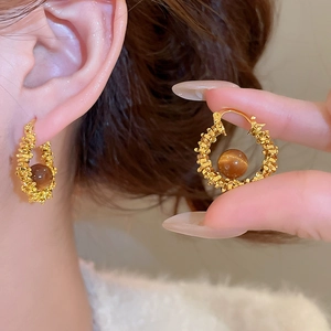 Detail of vintage gold textured hoop earrings with brown resin beads for women