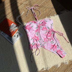 Detail of pink floral bikini with gold bead side ties on a textured resort background