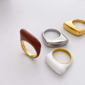 Detailed top view of geometric enamel rings in brown, white, gold, and silver finishes