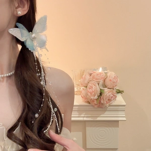 Detail of blue butterfly hair clip with beaded tassels and pearl accent on wavy hair