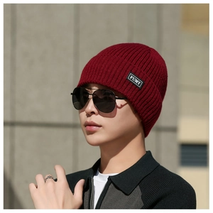 Detail of burgundy rib-knit beanie showing thick warm fabric and black FUMY brand label
