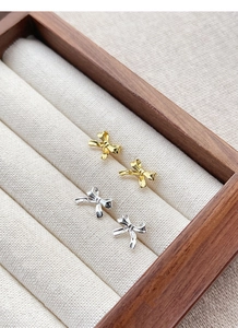 Detailed view of gold and silver S925 sterling silver bow knot stud earrings in a jewelry box