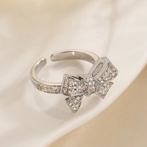 Detail of silver bow ring with shimmering pavé rhinestones on soft beige fabric