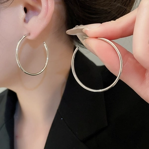 Macro shot of large polished silver hoop earrings styled with a black blazer