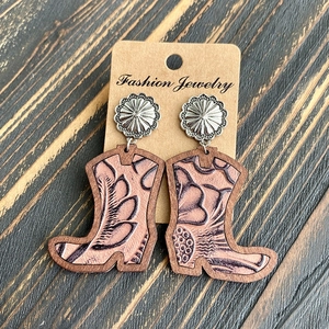 Macro detail of western cowboy boot earrings with leopard print and wooden texture
