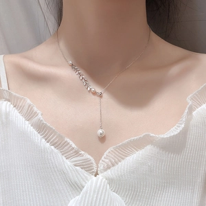 Detail of Y-shaped silver necklace with pearl accents and micro-set leaf charms on a model