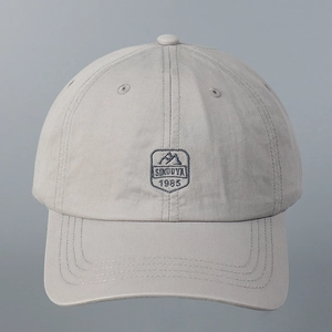 Detailed view of grey cotton baseball cap with blue SINDUYA 1985 embroidery and stitching