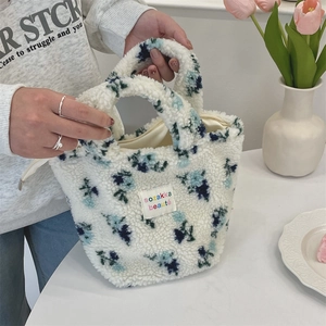 Detail einer floralen Plüschhandtasche mit Reißverschluss und buntem gewebtem Logo-Patch