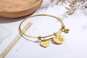 Adjustable golden stainless steel heart bangle with Love engraving and girl charm detail