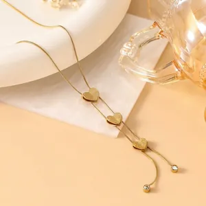 Detailed macro view of 18K gold snake chain necklace with matte heart charms and zircons