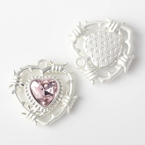 Macro detail of heart-shaped alloy pendant with pink crystal and thorn wire design