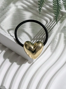 Detail of high-elastic black hair tie featuring a polished gold metallic heart charm