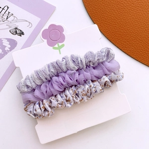 Lot de trois chouchous violets à fleurs et volants sur carte de support Vogue Girl