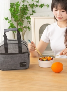 Detail of grey insulated lunch bag with durable handles on a natural wooden table