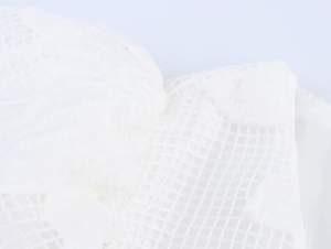 Detailed macro view of white floral lace fabric and mesh embroidery on puffy sleeves