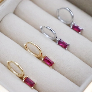 Macro shot of S925 silver hoop earrings with rectangular red ruby pendants in gold and silver