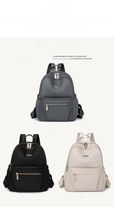Three travel backpacks in gray, black and cream white with gold zippers and nylon fabric