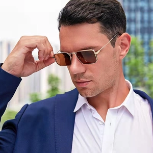 Close-up of high-end gold metal rectangle sunglasses with brown lenses on a male model