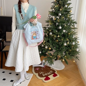 Detailed lifestyle shot of light blue quilted tote bag with cute embroidery and pink straps