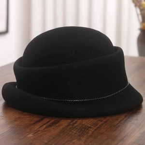 Close-up of black wool fedora with a delicate bead chain trim on dark wood table