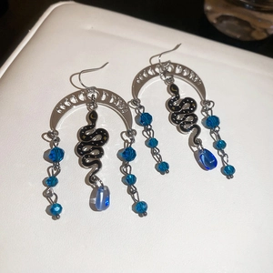 Detailed macro view of Gothic snake and moon pendant earrings with blue crystal beads