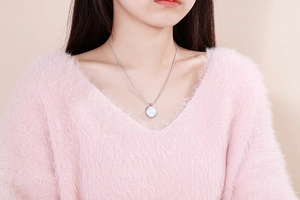 Close-up of Scorpio constellation pendant necklace worn on a soft pink sweater
