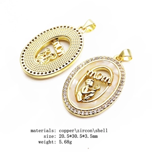 Detailed view of gold oval MOM pendants with zircons and shell inlay on white background