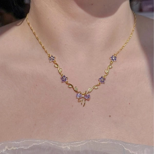 Detail einer goldenen Rebenkette mit lila Blumensteinen und einer Kristallschleife