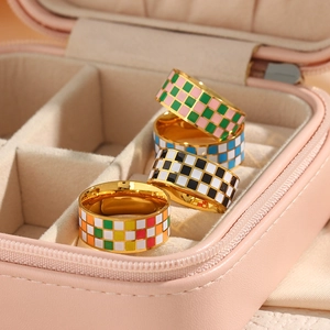 Close-up of four gold stainless steel rings with checkered enamel patterns in a jewelry box