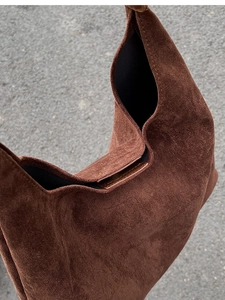 Detail of dark brown matte suede hobo bag with textured finish and slouchy design