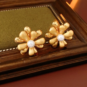 Detailed macro view of 18k gold plated flower earrings with pearl on green velvet