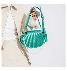 Details der metallisch grünen Muschel-Tasche mit Perlenkette an einem Model