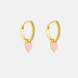 Détail de boucles d'oreilles cœur dorées avec émail rose et pierres en zircon