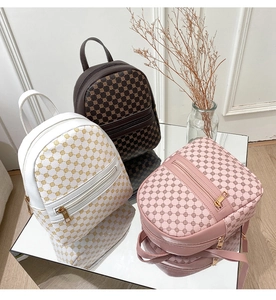 Detailed macro view of mini printed backpacks in white, brown and pink synthetic leather