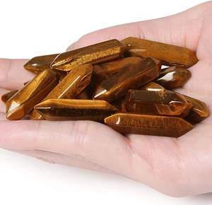 Polished tiger eye double-pointed hexagonal crystal columns held in hand for size reference